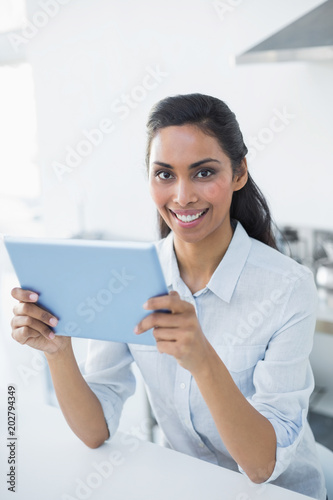 Attractive peaceful woman holding her tablet smiling cheerfully at camera