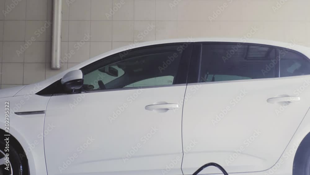 Manual car wash with foam. A man washes the car with water. He washes the foam off the car. 4k