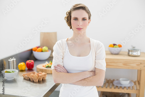 Peaceful serious woman standing with arms crossed in kitchen