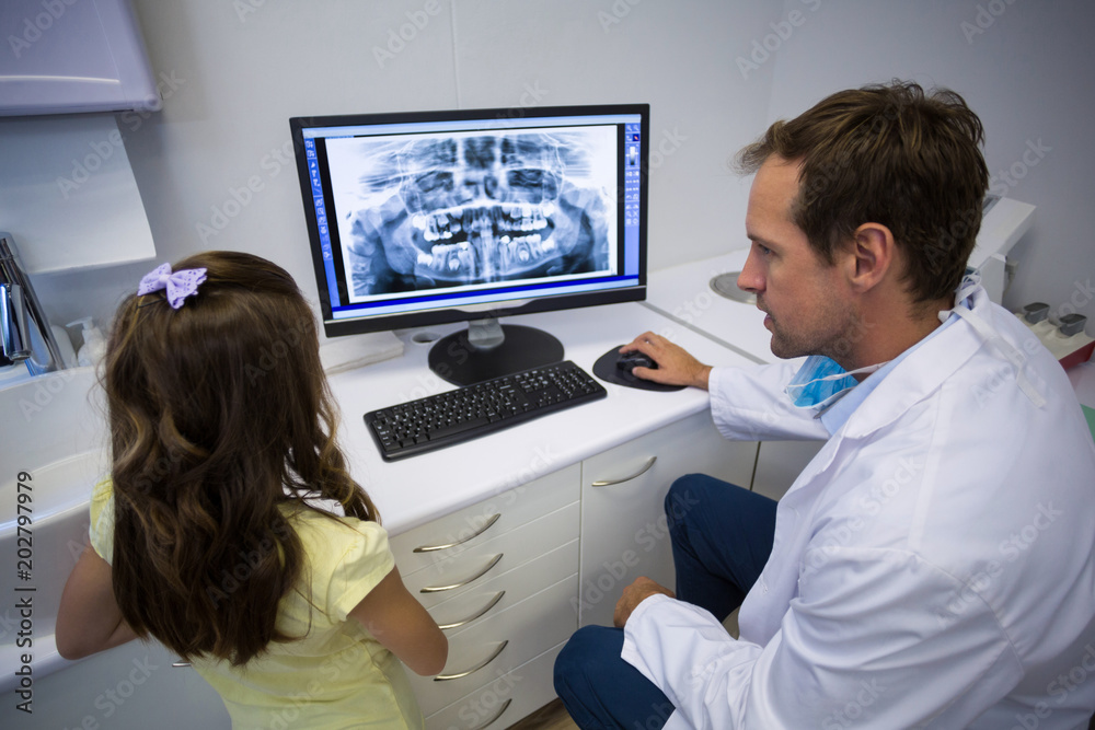 Dentist showing x-ray on computer to young patient