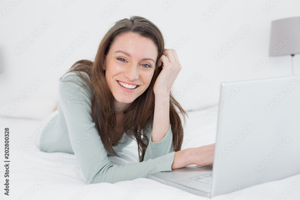 Cheerful relaxed casual young woman with laptop in bed Cheerful relaxed casual young woman with laptop in bed