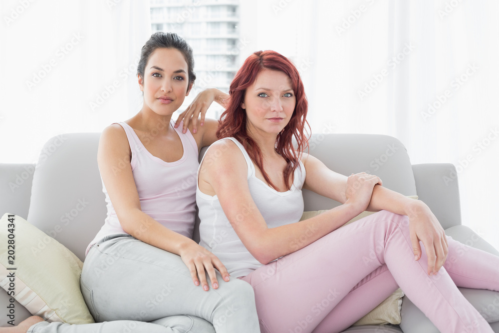 Two serious beautiful female friends sitting in the living room Two serious beautiful female friends sitting in the living room