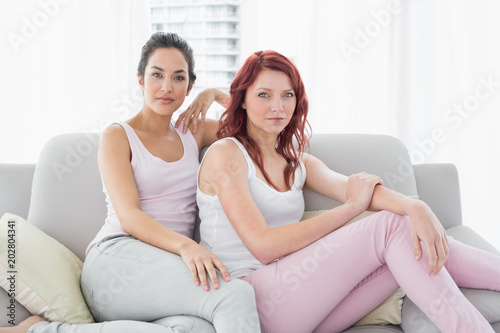 Two serious beautiful female friends sitting in the living room