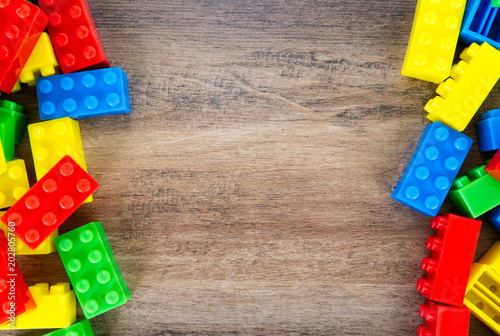 Colorful toy building blocks on wood background.