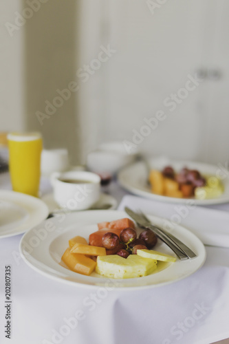 hotel breakfast table with plate of fruit  coffees and orange juices