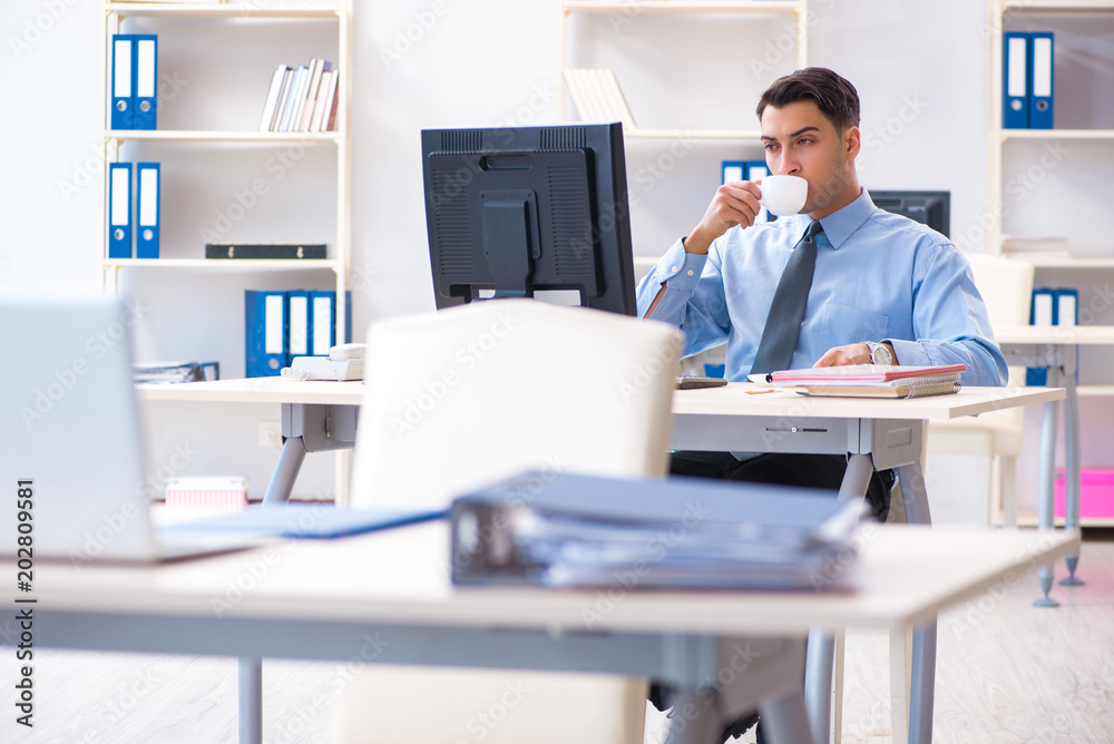 Handsome businessman employee sitting at his desk in office Handsome businessman employee sitting at his desk in office