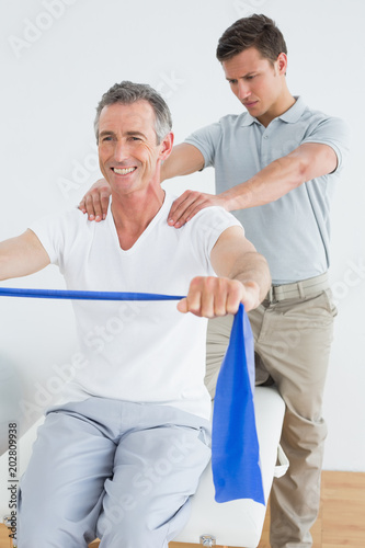 Therapist massaging a mans shoulder in gym hospital