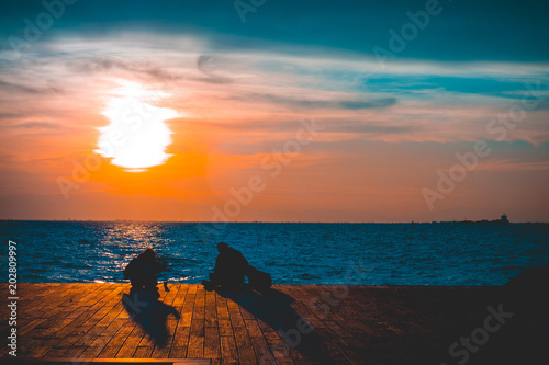 Two people watching a bright orange ocean sunset