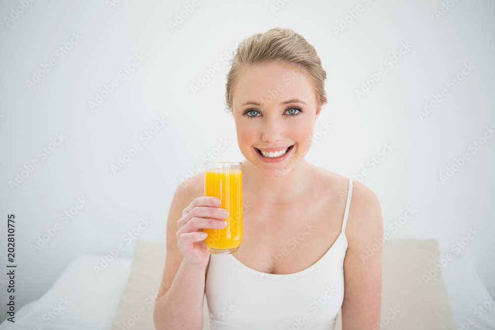 Natural cheerful blonde holding glass of orange juice Natural cheerful blonde holding glass of orange juice