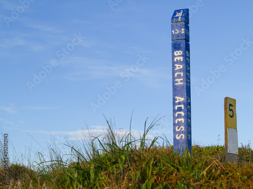 Blue beach access sign on Papamoa dunes.