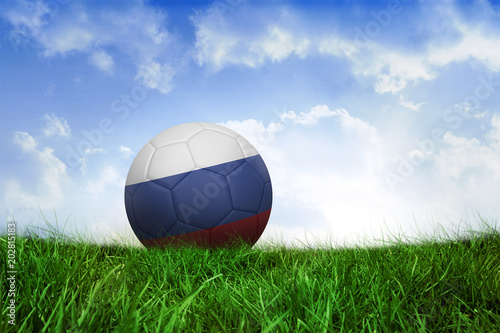 Football in russia colours on field of grass under blue sky