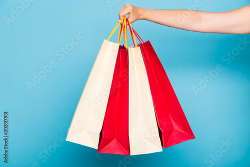 people, sale and consumerism concept - close up of female hand with shopping bags over white background
