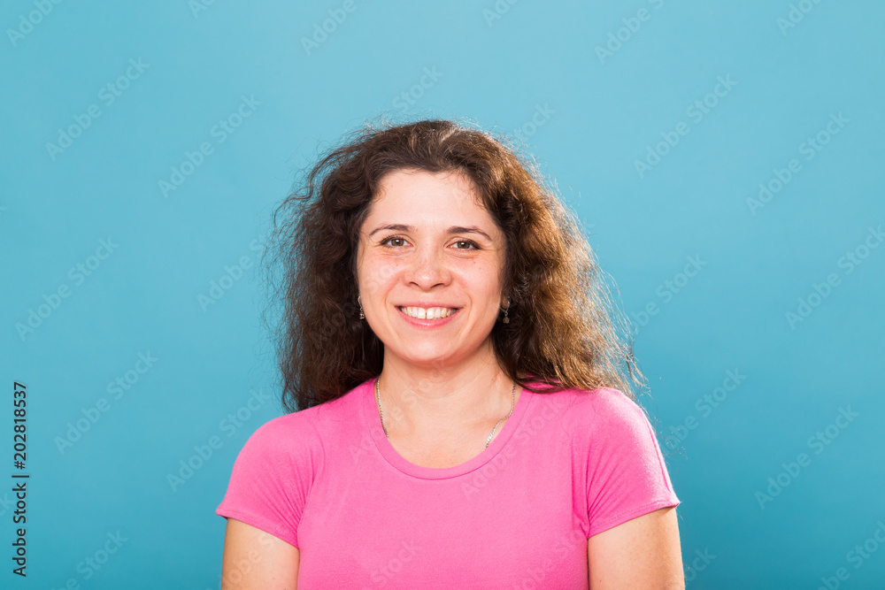 Close up portrait of a beautiful young woman with curly hair on blue background Close up portrait of a beautiful young woman with curly hair on blue background