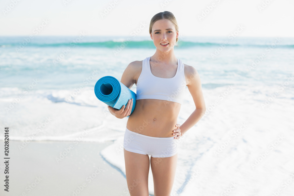 Attractive slender woman holding rolled up exercise mat Attractive slender woman holding rolled up exercise mat