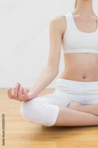 Mid section of slender fit woman meditating sitting in lotus position