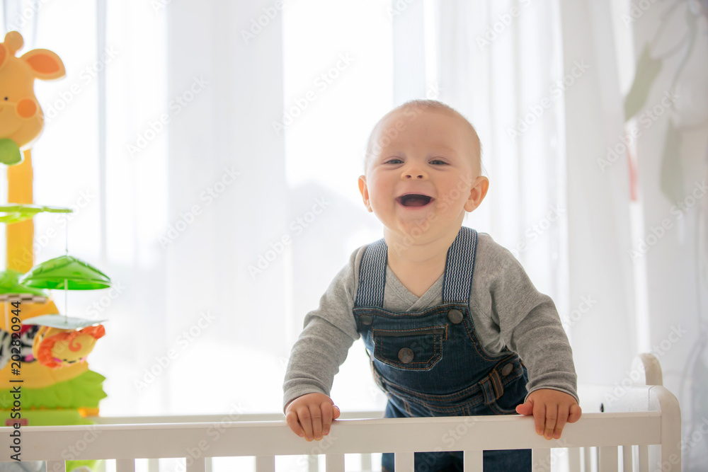 Smiling toddler boy, playing with little rabbit toy in crib Smiling toddler boy, playing with little rabbit toy in crib