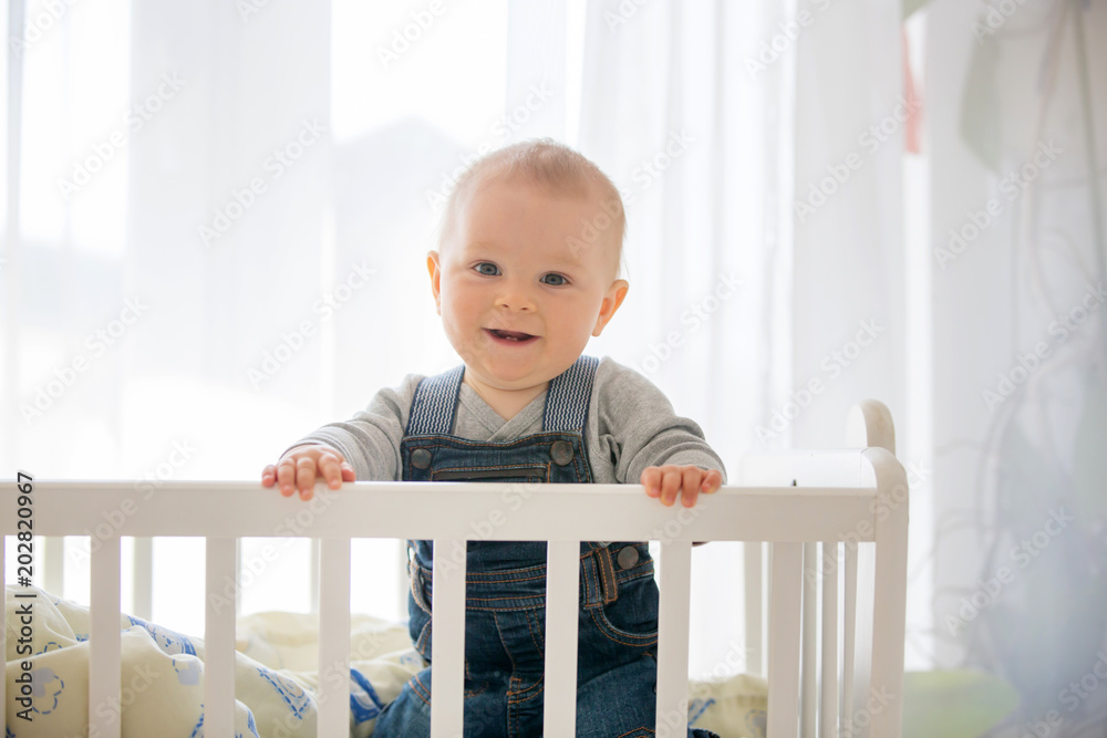 Smiling toddler boy, playing with little rabbit toy in crib Smiling toddler boy, playing with little rabbit toy in crib