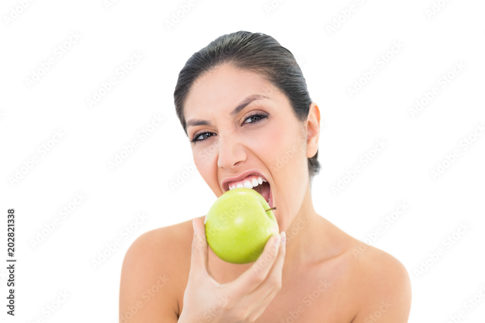 Happy brunette eating a green apple and looking at camera Happy brunette eating a green apple and looking at camera
