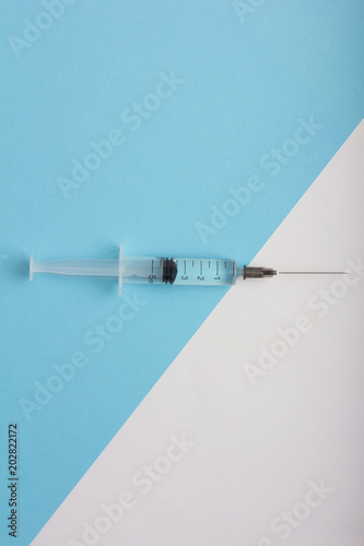 syringe with medication on a diagonal white blue background. Vertical view
