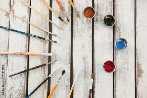 Paintbrushes and watercolors arranged on wooden surface