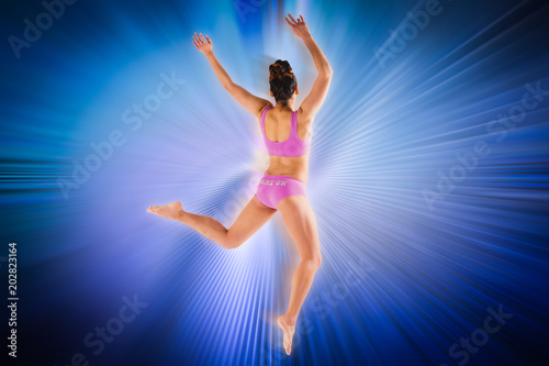 Fit brunette jumping and posing against abstract background
