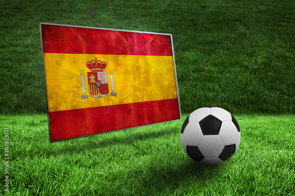 Fototapeta premium Black and white football on grass against spain flag in grunge effect