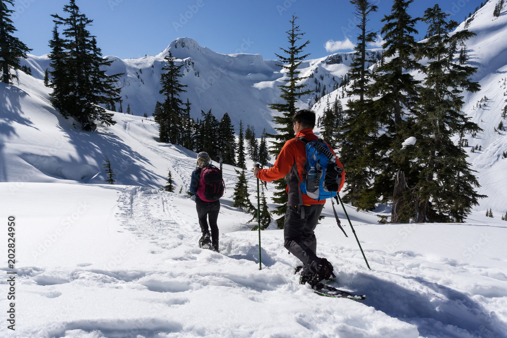 Adventurous man and woman are snowshoeing in the snow. Taken in Artist Point, Northeast of Seattle, Washington, United States of America.