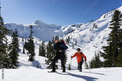 Adventurous man and woman are snowshoeing in the snow. Taken in Artist Point, Northeast of Seattle, Washington, United States of America.