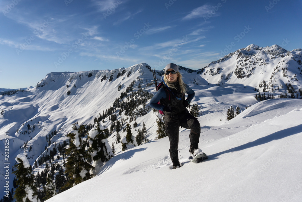 Adventurous woman is snowshoeing in the beautiful mountainous landscape. Taken in Artist Point, Northeast of Seattle, Washington, United States of America.