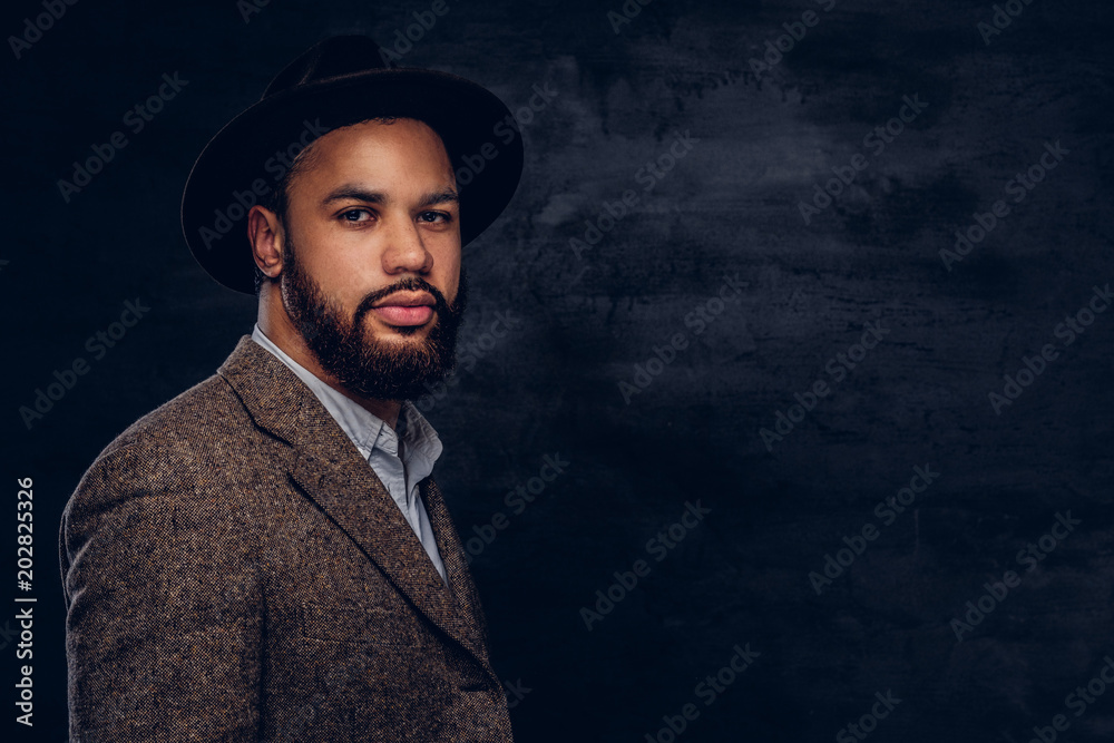Studio portrait of handsome Afro-American male in an elegant brown jacket and hat. Studio portrait of handsome Afro-American male in an elegant brown jacket and hat.