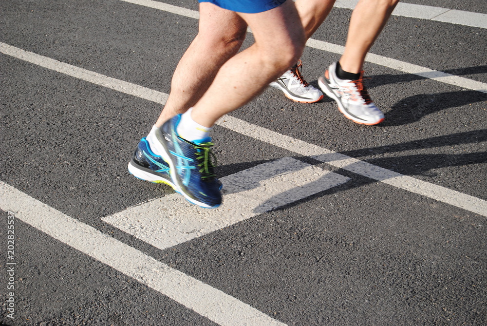 Corrida, pés de duas pessoas a correr em pista de corrida com sapatilhas calçadas, praticar desporto, maratona