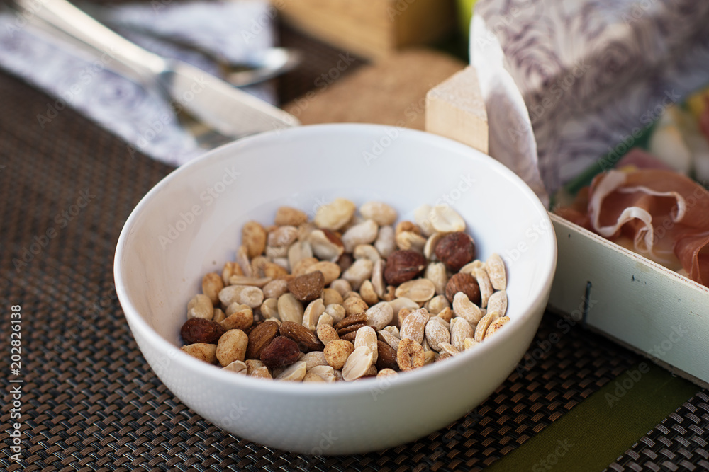 bowl of mixed assorted salted nuts on a table served out doors al fresco dinning