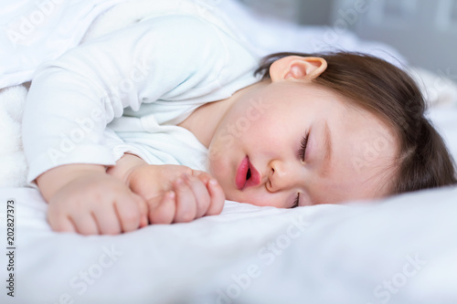 Sleepy toddler boy sleeping on his bed