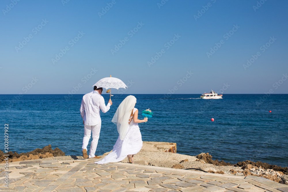 Bride and groom by the sea on their wedding day Bride and groom by the sea on their wedding day