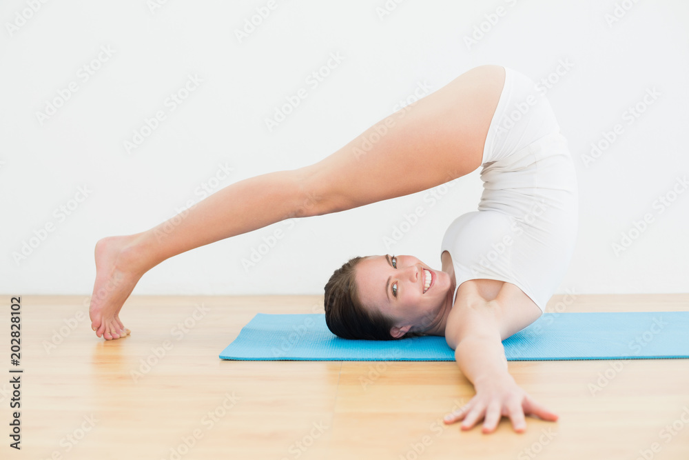Side view of a smiling woman exercising on mat Side view of a smiling woman exercising on mat