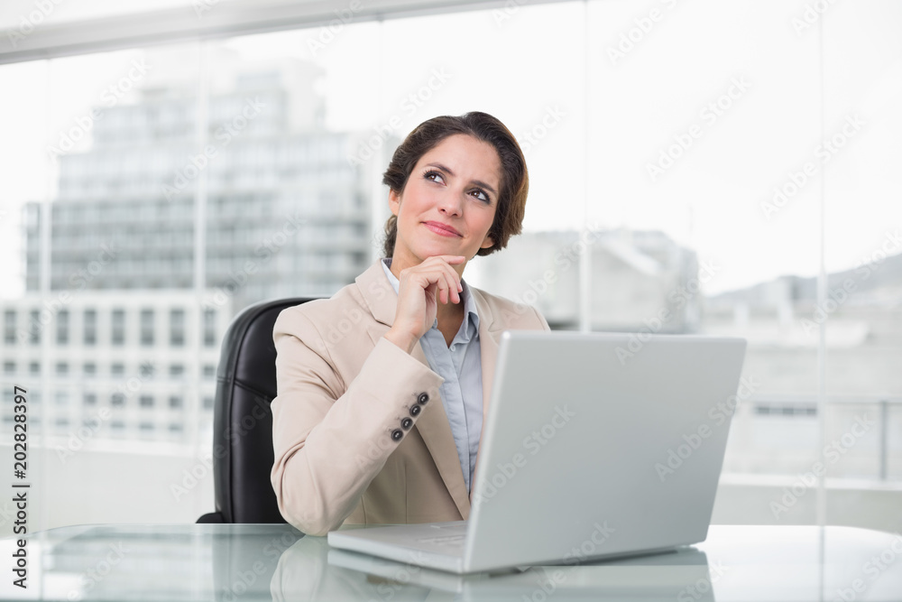 Thoughtful businesswoman using laptop at her desk Thoughtful businesswoman using laptop at her desk