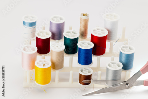 Many spools of different colored thread used for sewing and a pair of scissors