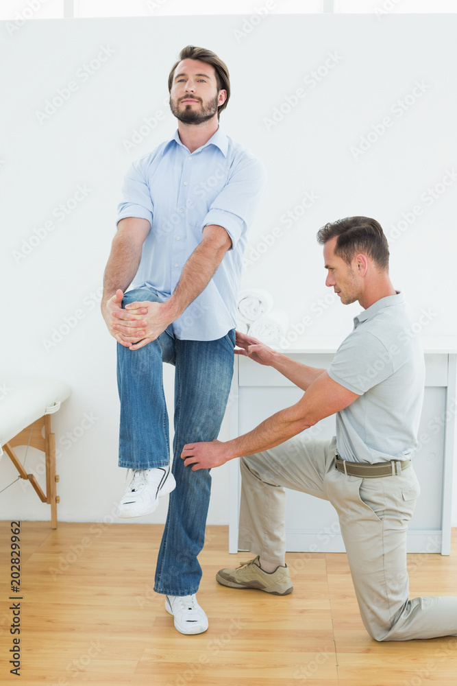 Therapist assisting young man with stretching exercises Therapist assisting young man with stretching exercises