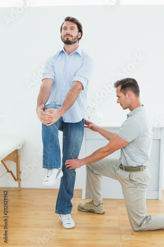 Therapist assisting young man with stretching exercises