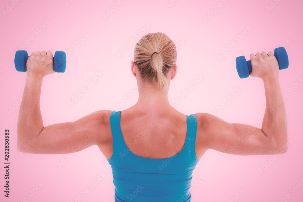 Rear view of muscular woman lifting dumbbells against pink background Rear view of muscular woman lifting dumbbells against pink background