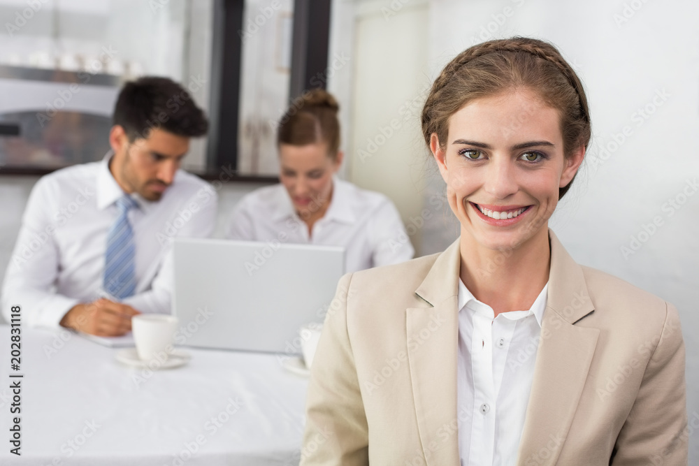 Smiling businesswoman with colleagues at office desk Smiling businesswoman with colleagues at office desk