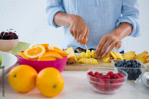 Mid-section of woman cutting fruits on chopping board
