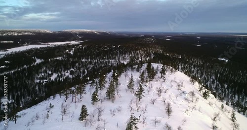 Aerial view over a fell mountain, revealing arctic tundra wilderness, near luostotunturi fjeld, on a sunny winter morning dusk, Pyha-luosto national park, Lapland, Finland.mp4 photo