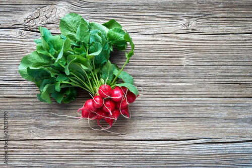 Fototapeta Naklejka Na Ścianę i Meble -  Organic food. Bunch of red radish on rustic wooden background. Top view, copy space. Healthy food