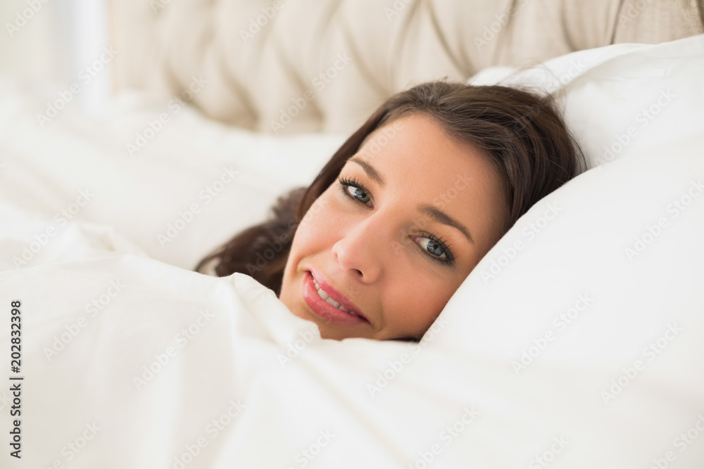 Smiling pretty brown haired woman relaxing in her bed Smiling pretty brown haired woman relaxing in her bed