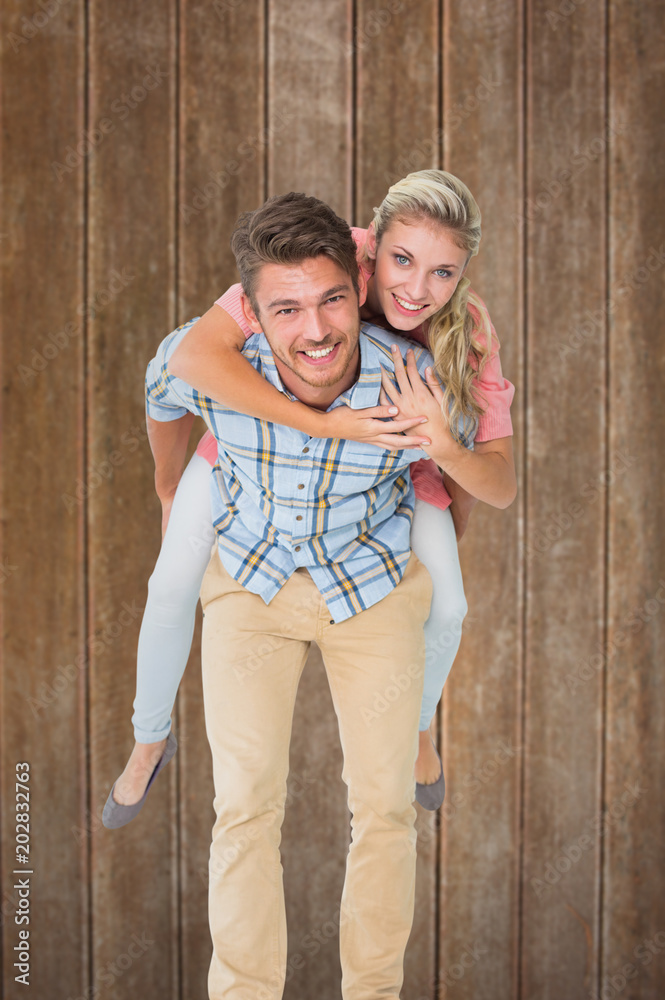 Φωτογραφία Handsome man giving piggy back to his girlfriend against wooden planks backgroun