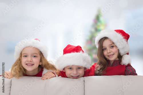 Cute siblings against blurry christmas tree in room