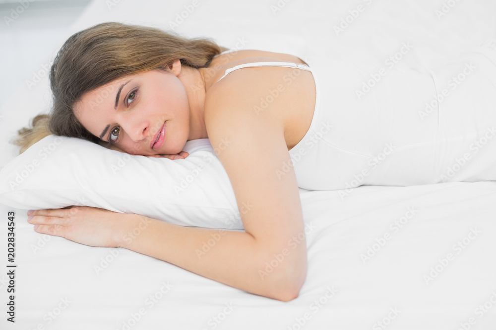 Pretty peaceful woman looking at camera lying on her bed Pretty peaceful woman looking at camera lying on her bed