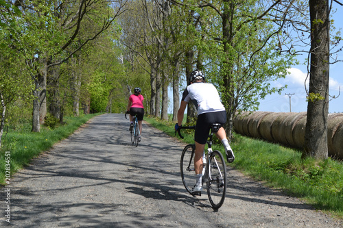 Spring bike riding through tree avenue, Young couple on bikes riding through tree avenue during beautiful spring day