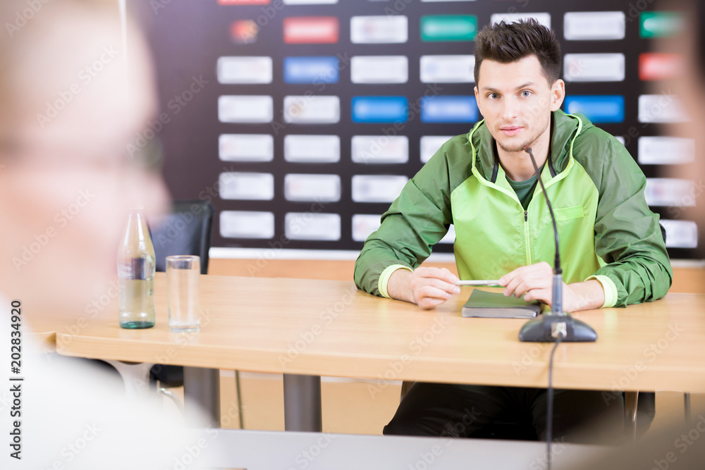 Φωτογραφία Portrait of young professional sportsman speaking to microphone at press confere